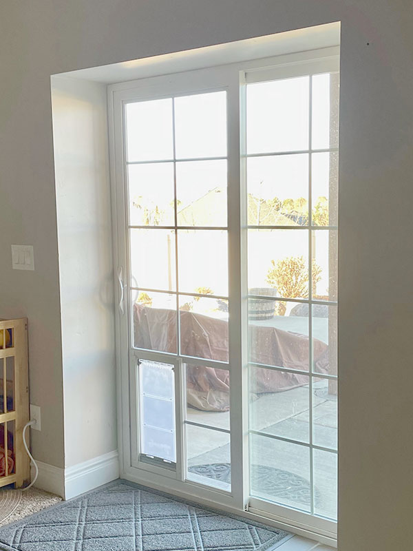 White sliding glass door with a pet door insert leading to a patio.