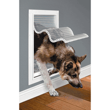 A German Shepherd dog is going through a dog door.