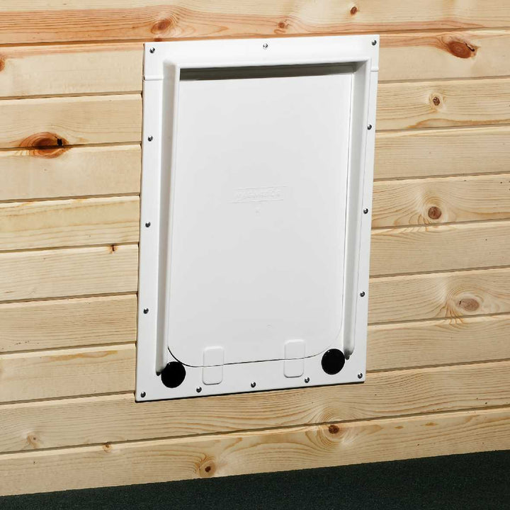 A white pet door is installed in a wood plank wall.