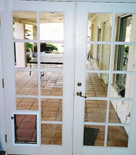 White French doors with a pet door on one side, leading to a brick patio.