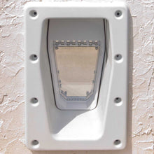 A white, rectangular pet door with a transparent flap is installed in a stucco wall.