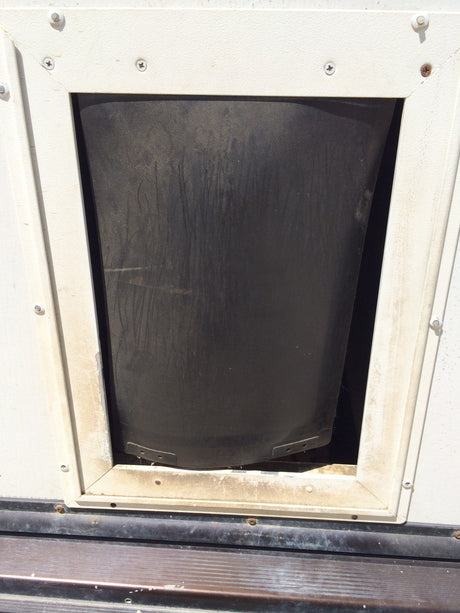 A dark, flexible flap in a white, framed opening.