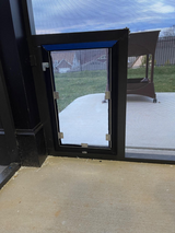 A dog door is installed in a screened-in porch.