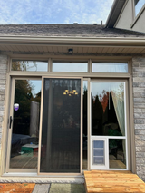 Exterior view of a glass sliding door with a screen and a pet door.