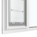 The bottom section of a white Thermo Sash 3e cat window door is shown closed within a window, highlighting its secure fit in a sash window. This insulated cat door helps seal the door sash.