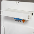 High Tech rechargeable battery for Roll Up power pet doors, a white rectangular plastic housing with a brass connector slot on the lower edge, photographed at a three-quarter overhead angle on a dark wooden surface.