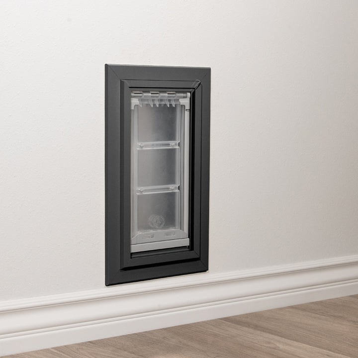 A pet door is installed in a white wall.