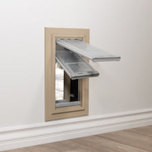 A pet door is installed in a white wall.