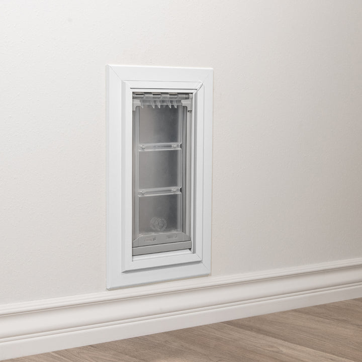 A pet door is installed in a white wall above the baseboard.