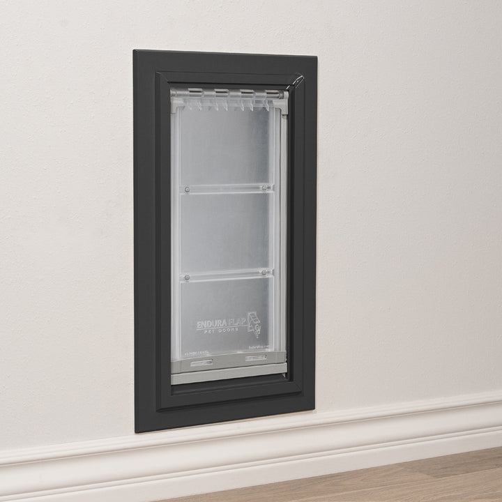 A black-framed "Endura Flap Pet Doors" pet door is installed in a wall.
