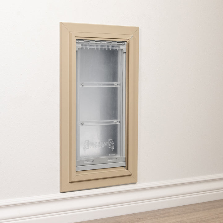 A beige-framed Endura Flap pet door is installed in a wall.