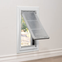 A white-framed pet door is installed in a wall, with the flap partially open, revealing a view of the outdoors.