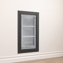 A DuraFlap pet door is installed in a white wall with white trim.