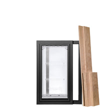 A black-framed pet door with transparent flaps stands beside a stack of unfinished wooden planks against a white background.
