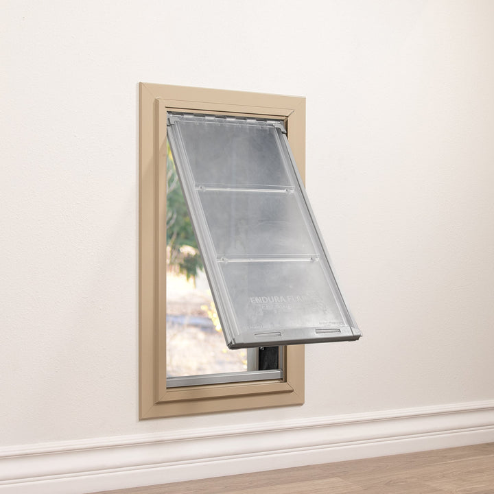 A pet door with a partially open transparent flap is installed in a wall.