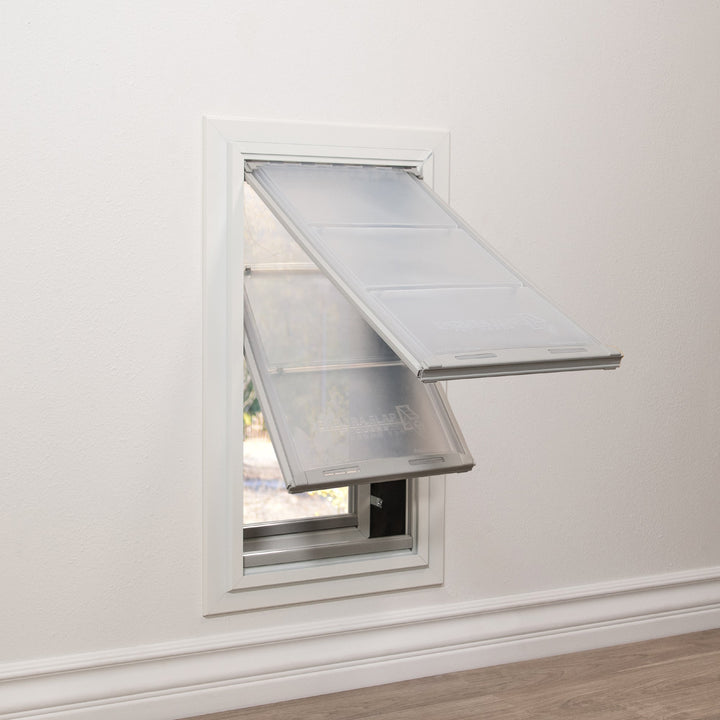 A dog door with two hinged flaps is installed in a wall.