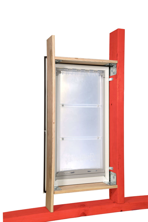 A white-framed pet door with a clear flap is mounted in a wooden structure with red and natural wood beams.