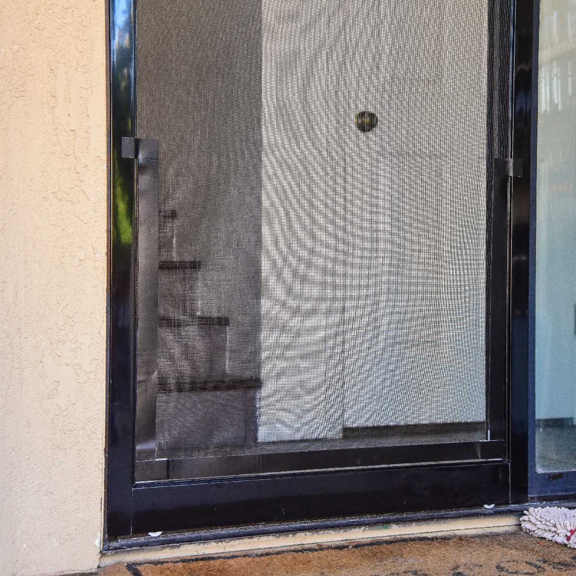 A close-up of a black-framed screen door.