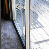 View through a sliding glass door onto a deck with a gray carpet inside.