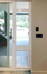 A sliding glass door with a dog door installed in a white frame.