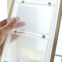 Hand holding a clear plastic page protector with pockets.