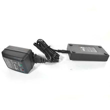 A black AC adapter and a small black electronic device connected by a wire.