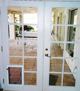 White French doors with a pet door on one side, leading to a brick patio.