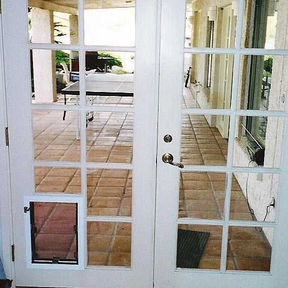 White French doors with a dog door in the lower-left panel open to a tiled patio.