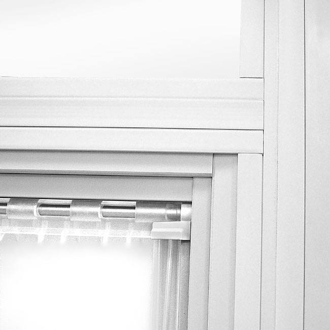 Close-up of white window frame with curtain rod and sheer curtain.