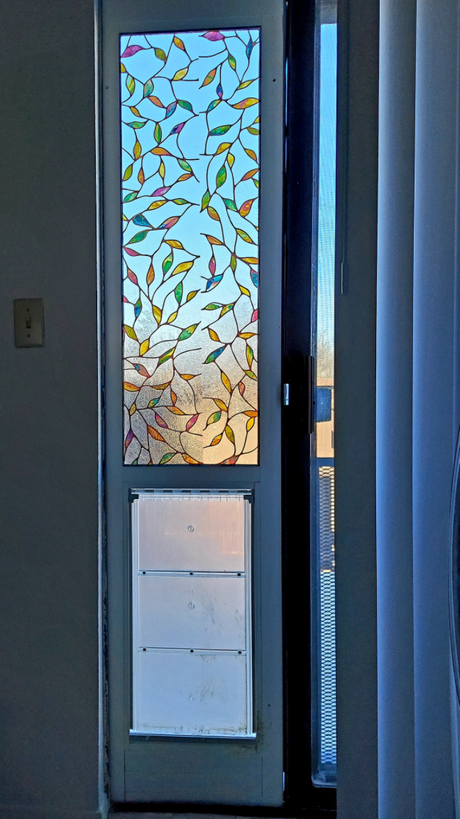 A door with stained glass in a leaf pattern and a pet door.