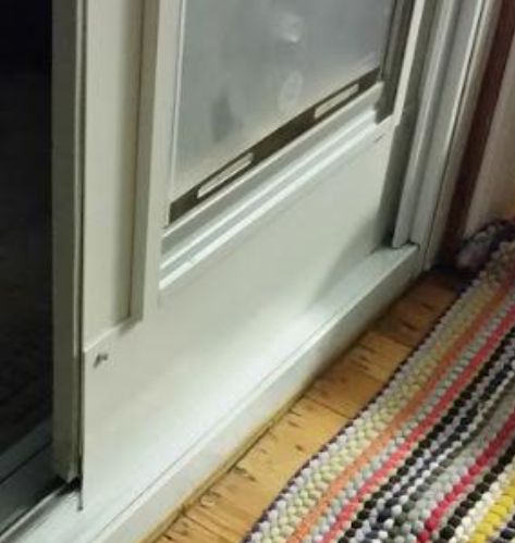 A white sliding glass door with a colorful rag rug nearby.