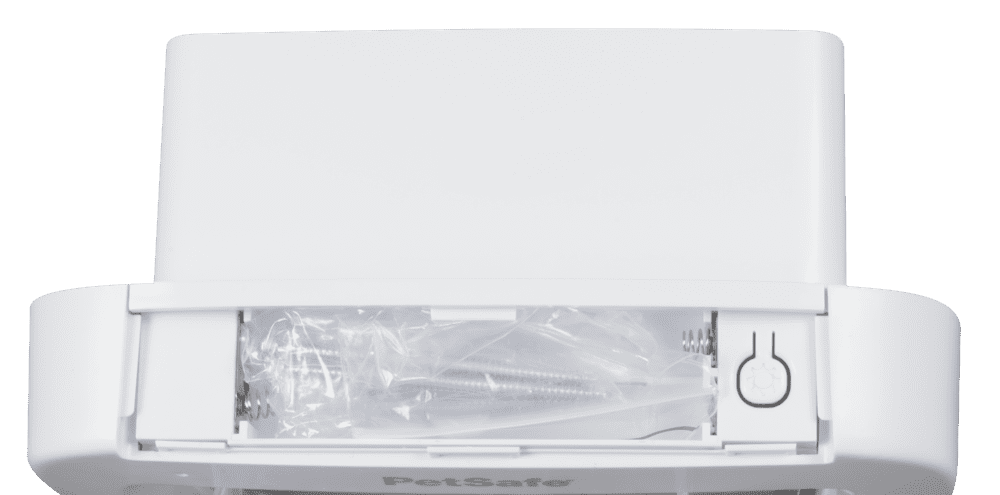 A white PetSafe device with screws and hardware in a plastic bag visible in a compartment.