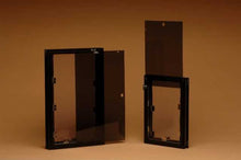 Two dark window frames with attached tinted glass panels on a brown background.