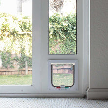 A white door with a dog door is installed next to a window.
